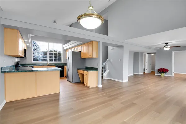 a view of a kitchen with kitchen island a sink wooden floor and a large window
