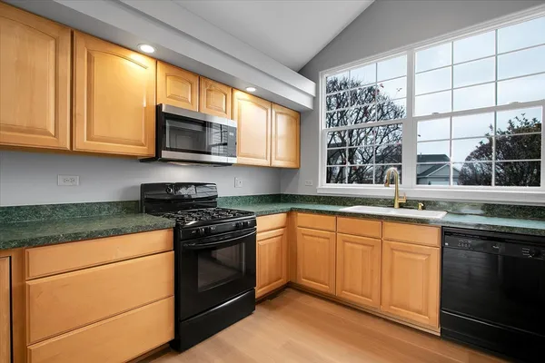 a kitchen with stainless steel appliances granite countertop a stove a sink and a microwave