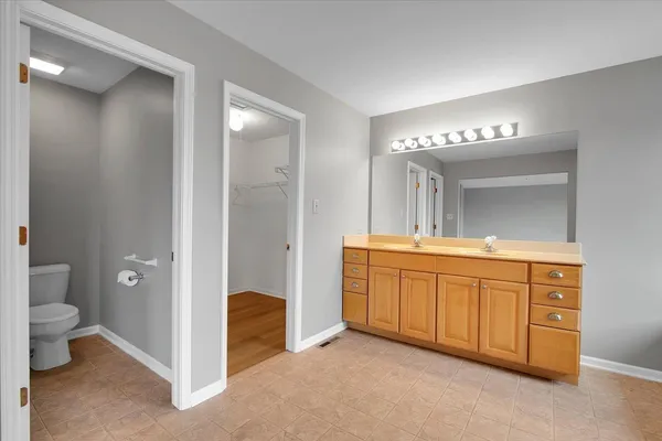 a spacious bathroom with a granite countertop sink a toilet and a mirror