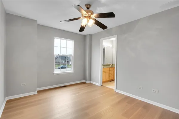 a view of an empty room with window and chandelier fan