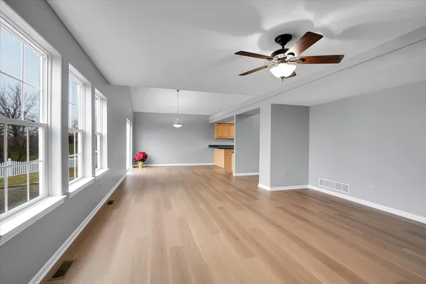 a view of empty room with wooden floor and fan