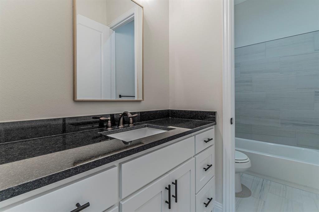 26 Kentucky Court Van Alstyne, TX 75495 - Photo 25 of 40 a bathroom with a granite countertop sink a toilet and bathtub