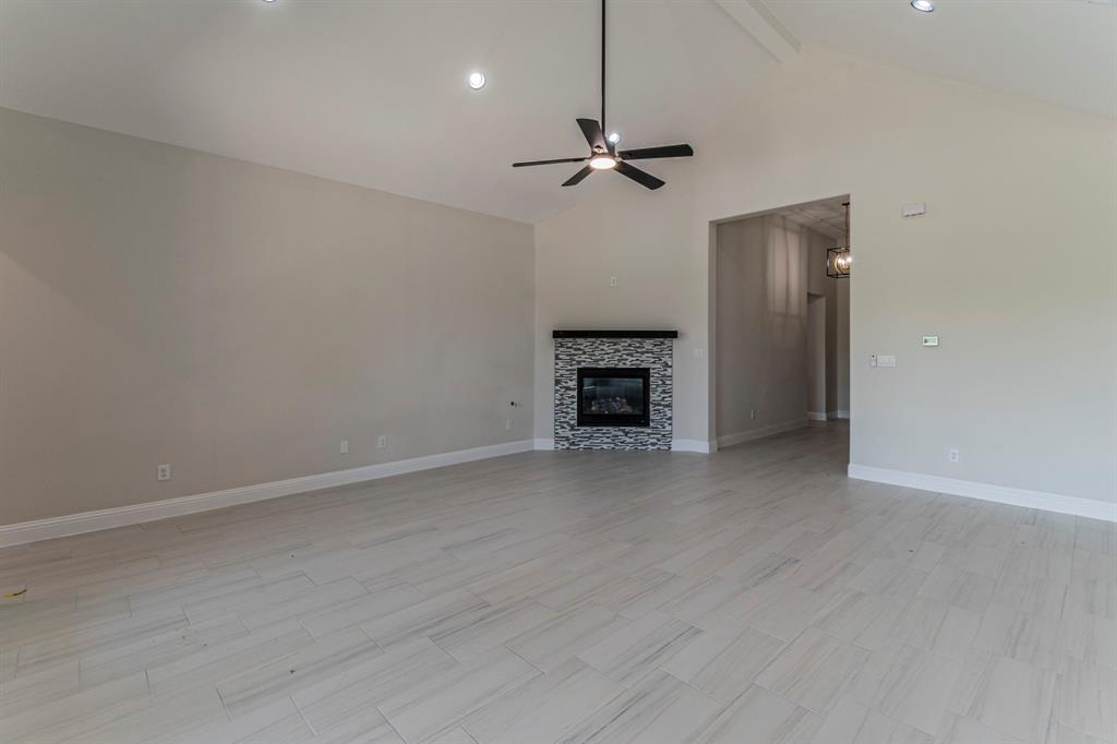 26 Kentucky Court Van Alstyne, TX 75495 - Photo 4 of 40 an empty room with fireplace and a ceiling fan
