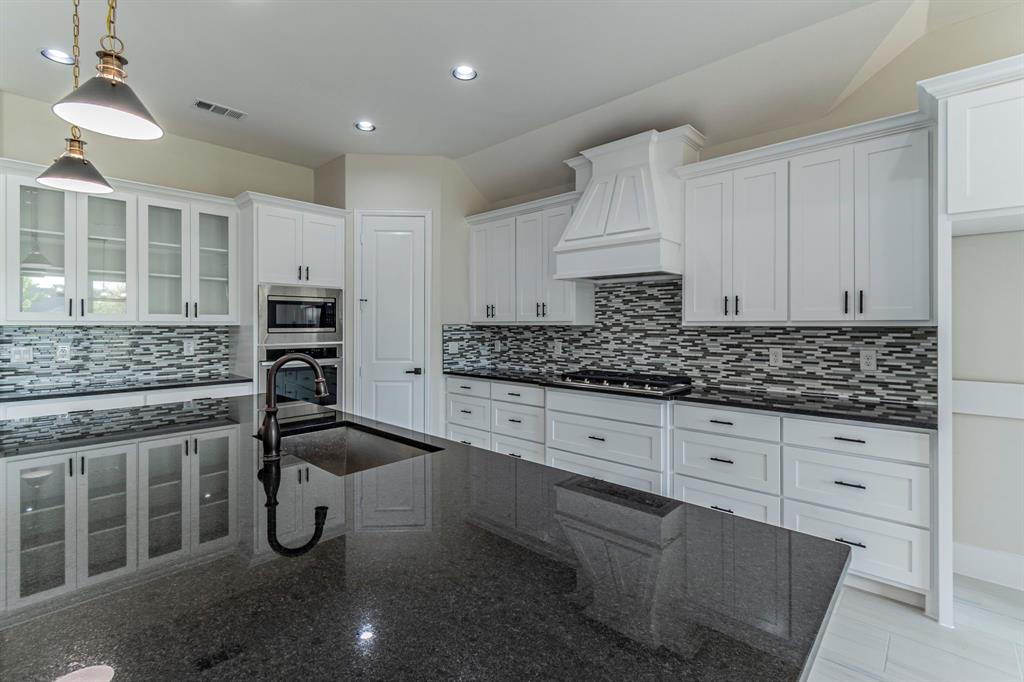 26 Kentucky Court Van Alstyne, TX 75495 - Photo 9 of 40 a kitchen with granite countertop a sink stove and cabinets