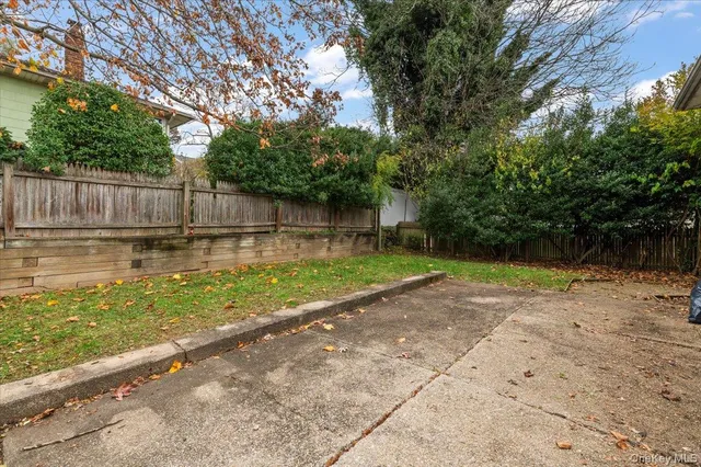 a view of a backyard with a large tree and wooden fence