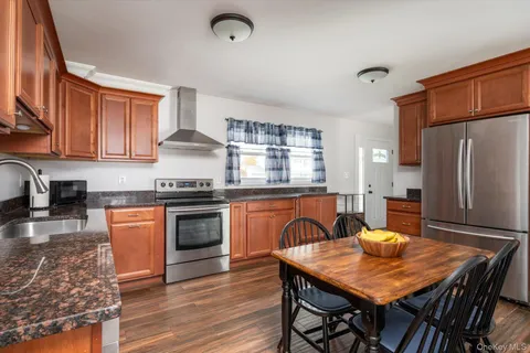 a kitchen with stainless steel appliances granite countertop a stove a refrigerator a sink a dining table and chairs with wooden floor
