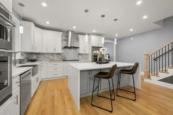 a kitchen with stainless steel appliances granite countertop a table chairs sink and cabinets