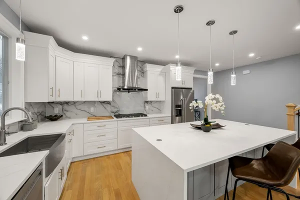 a kitchen with a sink a stove a refrigerator and white cabinets with wooden floor