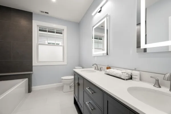 a bathroom with double vanity sink a mirror and a toilet