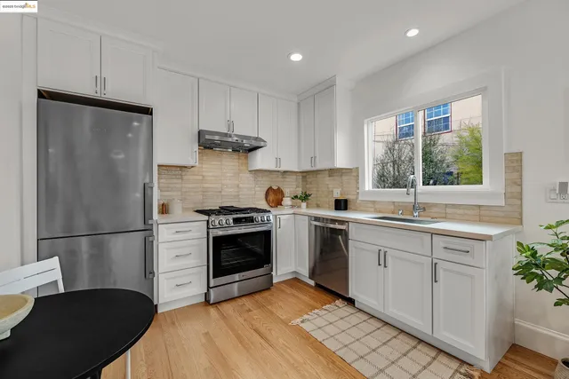 a kitchen with a stove and white cabinets with wooden floor