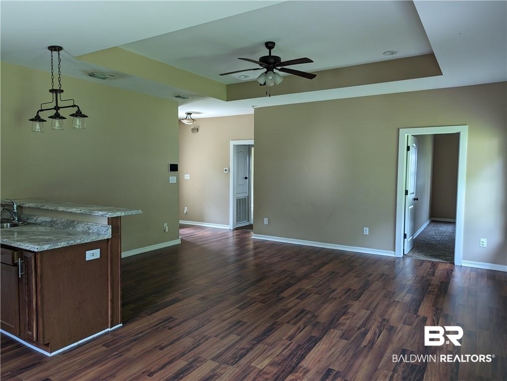 659 Bond Street Mobile, AL 36607 - Photo 2 of 10 Interior space featuring hanging light fixtures, dark hardwood / wood-style flooring, ceiling fan, and a raised ceiling