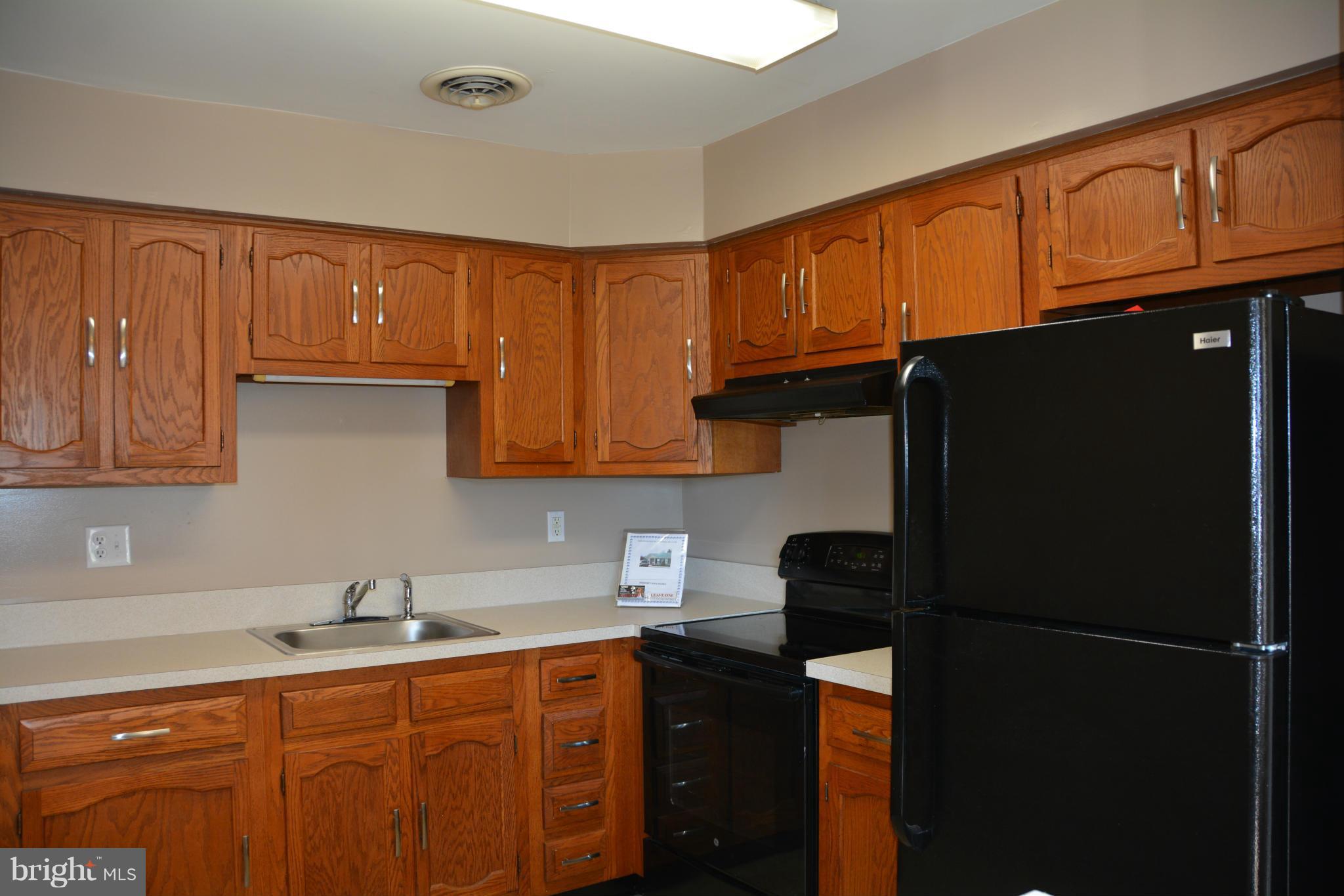 7004 Basswood Road Frederick, MD 21703 - Photo 2 of 16 a kitchen with stainless steel appliances granite countertop a refrigerator a sink dishwasher and wooden cabinets