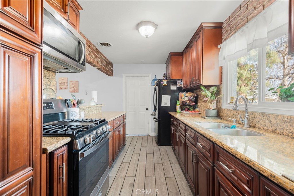 19450 Woodhill Street Rialto, CA 92376 - Photo 11 of 51 a kitchen with stainless steel appliances granite countertop a stove and a sink
