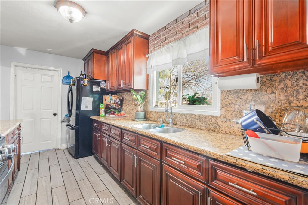 19450 Woodhill Street Rialto, CA 92376 - Photo 12 of 51 a kitchen with stainless steel appliances granite countertop a sink a stove and a wooden cabinets