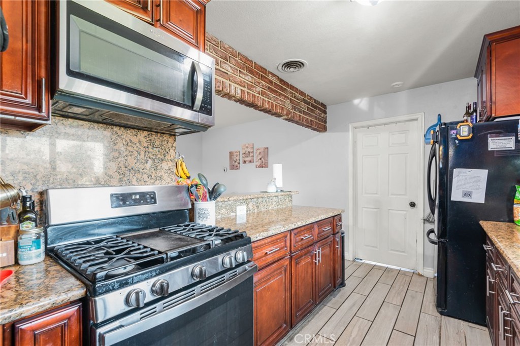19450 Woodhill Street Rialto, CA 92376 - Photo 13 of 51 a kitchen with stainless steel appliances granite countertop a stove and a microwave