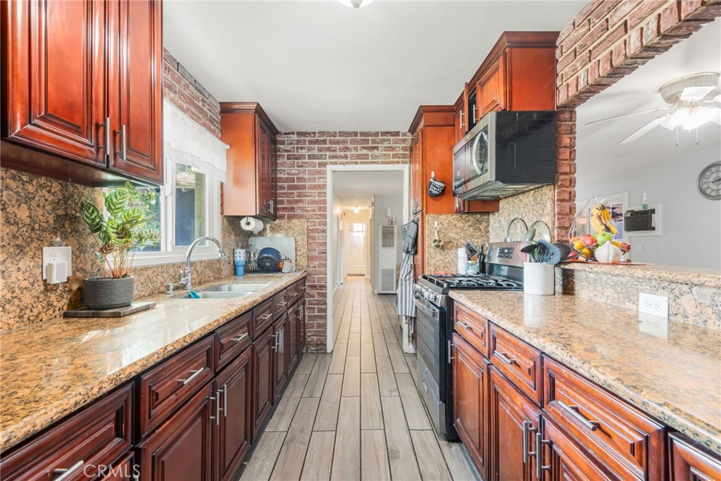 19450 Woodhill Street Rialto, CA 92376 - Photo 3 of 51 a kitchen with stainless steel appliances granite countertop a sink a stove and a wooden cabinets