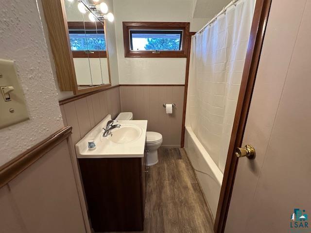 30 Fir Circle Babbitt, MN 55706 - Photo 13 of 27 Full bathroom featuring vanity, dark wood-type flooring, shower / bath combo with shower curtain, and a wainscoted wall