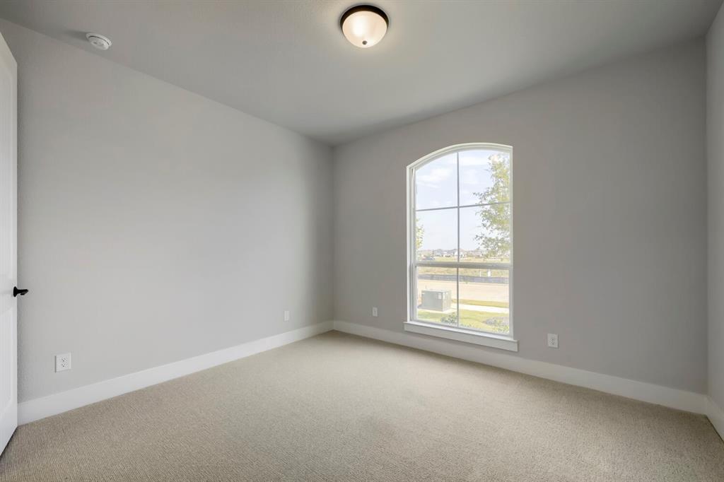 800 Blackberry Road Haslet, TX 76052 - Photo 10 of 28 Room featuring a large arched window with grid-patterned panes, light gray wall tones, neutral carpeting, and white baseboards
