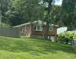 a backyard of a house with table and chairs wooden fence and large trees