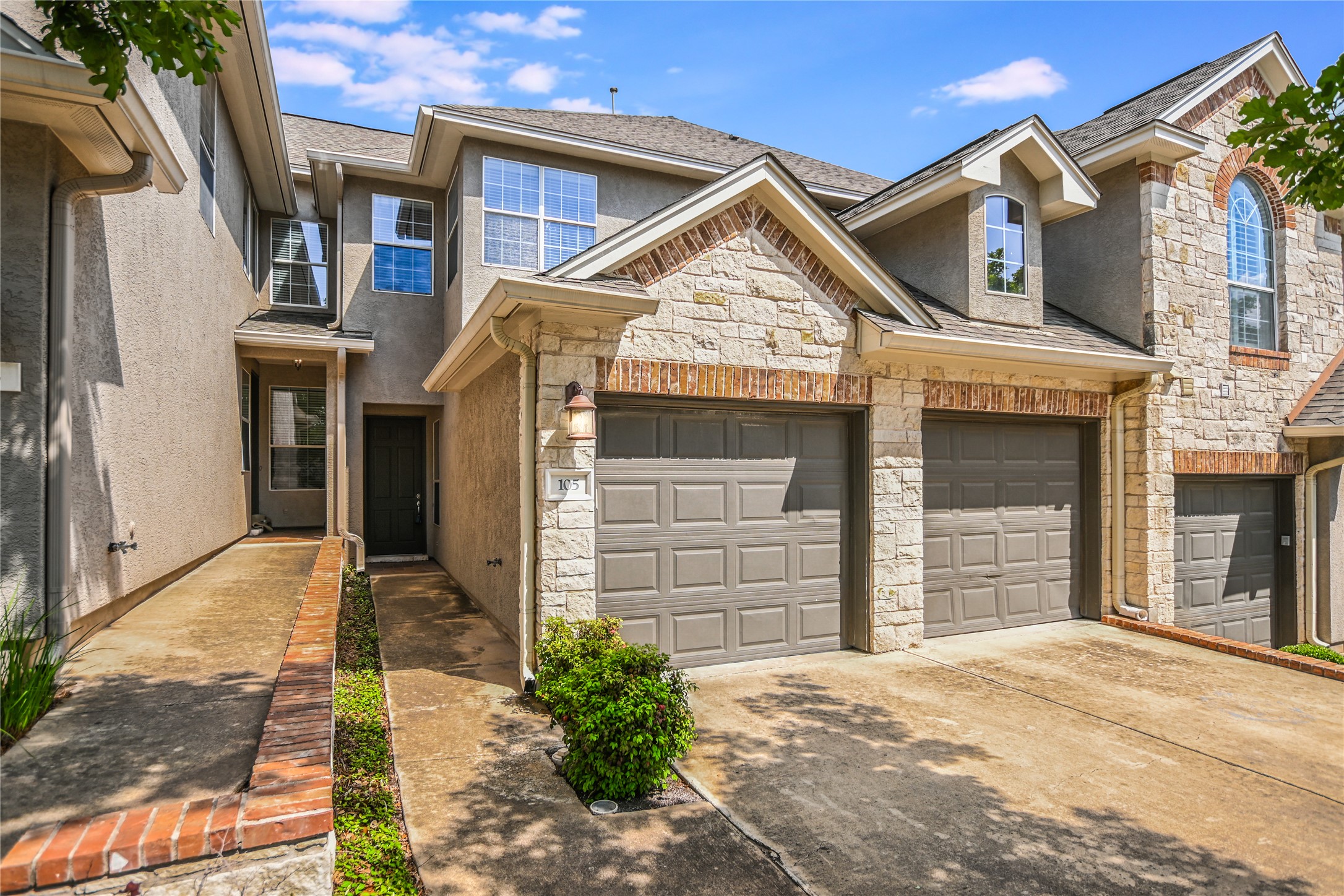 105 Aria Ridge, Unit 105 Austin, TX 78738 - Photo 1 of 1 View of property featuring stone siding, stucco siding, and driveway