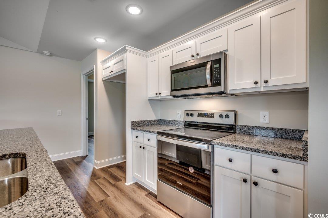4911 Joyner Swamp Road Galivants Ferry, SC 29544 - Photo 12 of 28 Kitchen with white cabinetry, wood-type flooring, stainless steel appliances, and stone countertops