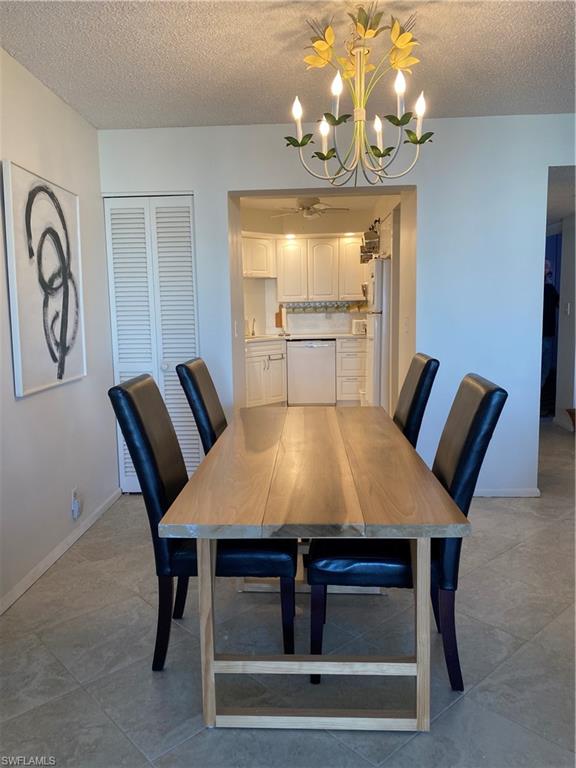 3 Bluebill Avenue, Unit 609 Naples, FL 34108 - Photo 7 of 15 Unfurnished dining area featuring tile patterned flooring, a textured ceiling, and a notable chandelier