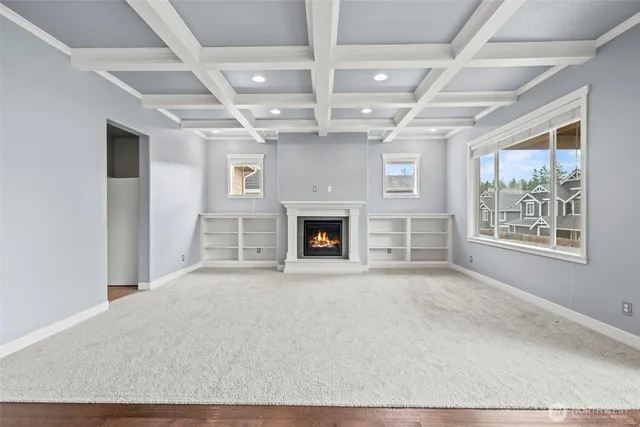 a view of an empty room with wooden floor and a fireplace