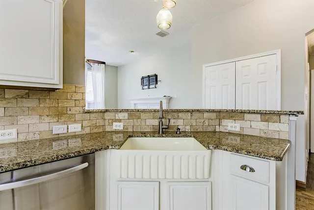 a kitchen with granite countertop a sink a stove and cabinets