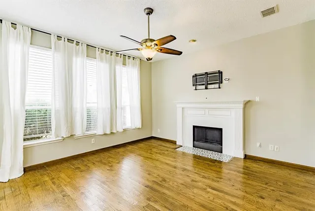 a view of empty room with fireplace and wooden floor