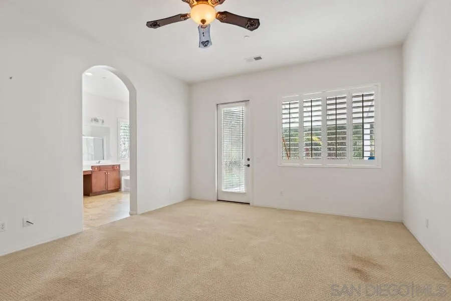 15076 Eastvale Road Poway, CA 92064 - Photo 19 of 35 an empty room with chandelier fan and windows