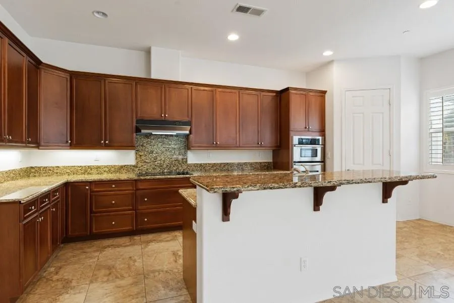 15076 Eastvale Road Poway, CA 92064 - Photo 7 of 35 a kitchen with stainless steel appliances granite countertop wooden cabinets a sink and dishwasher