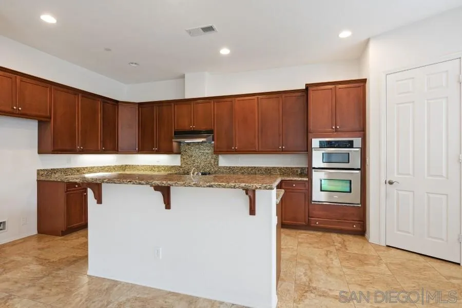 15076 Eastvale Road Poway, CA 92064 - Photo 8 of 35 a kitchen with stainless steel appliances granite countertop a table chairs sink and cabinets