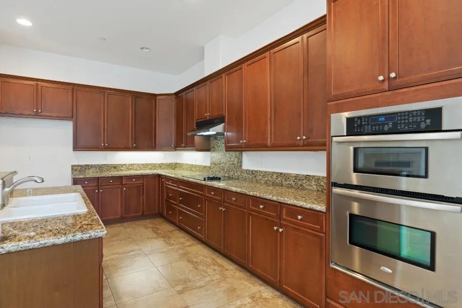 15076 Eastvale Road Poway, CA 92064 - Photo 9 of 35 a kitchen with granite countertop wooden cabinets and stainless steel appliances