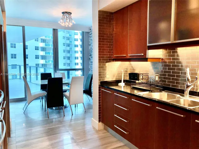 a kitchen with stainless steel appliances wooden floors wooden cabinets a dining table and chairs