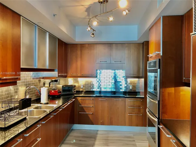 a kitchen with stainless steel appliances granite countertop a refrigerator a sink dishwasher a stove and white cabinets