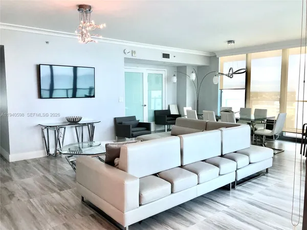 a living room with furniture kitchen view and large windows