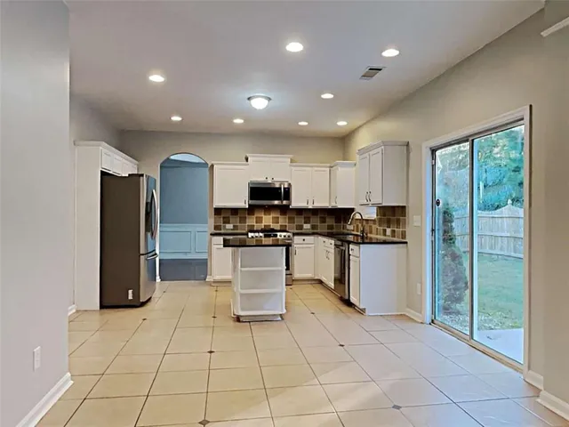 a kitchen with stainless steel appliances kitchen island granite countertop a refrigerator and a sink