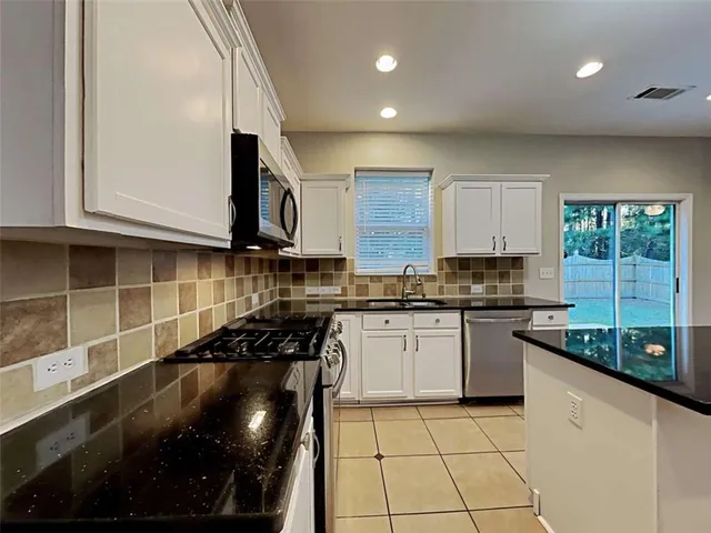 a kitchen with granite countertop a sink a stove and cabinets