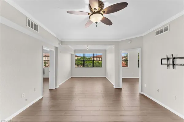 a view of an empty room with window and wooden floor