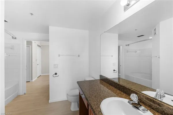 a bathroom with a granite countertop sink a mirror and a toilet