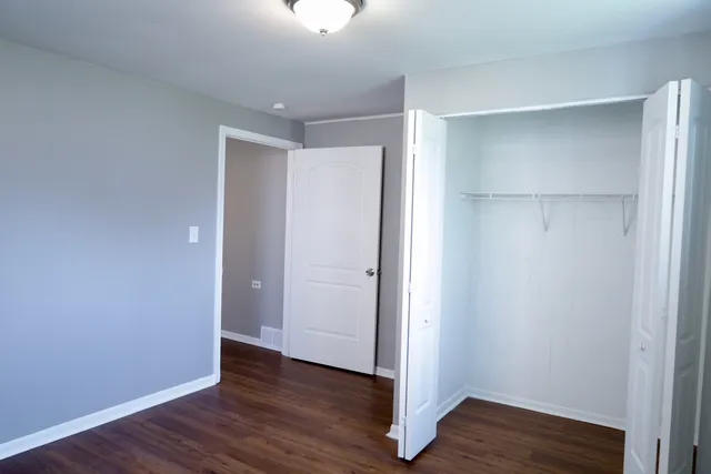 a view of an empty room with wooden floor & closet area