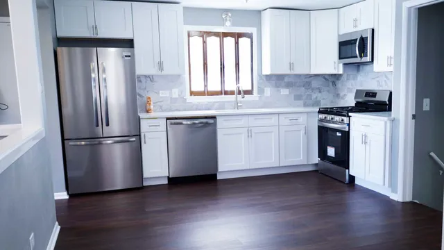 a kitchen with stainless steel appliances granite countertop a refrigerator a sink a stove a microwave and wooden floor