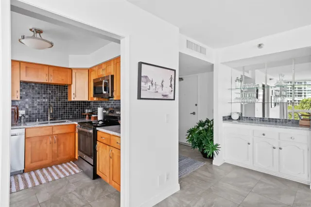 a kitchen with stainless steel appliances granite countertop a refrigerator a sink and white cabinets