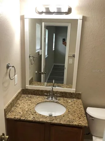 a bathroom with a granite countertop toilet sink and mirror