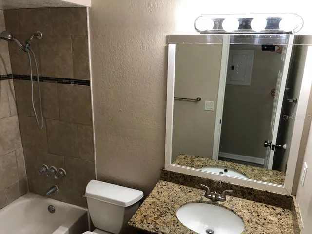 a bathroom with a granite countertop toilet sink and mirror