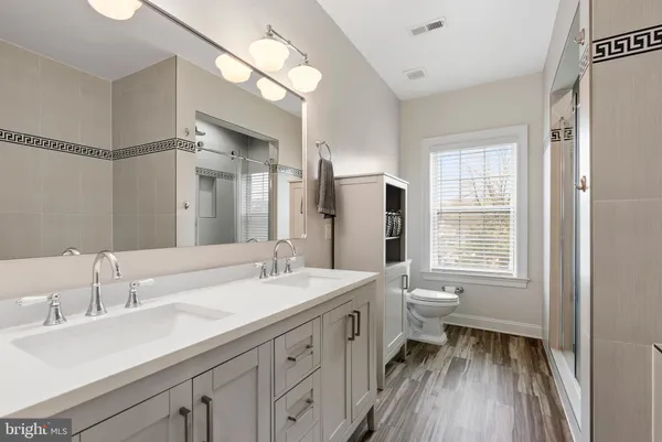 a bathroom with a double vanity sink a toilet and a mirror