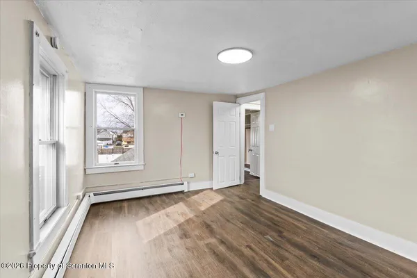an empty room with wooden floor and windows