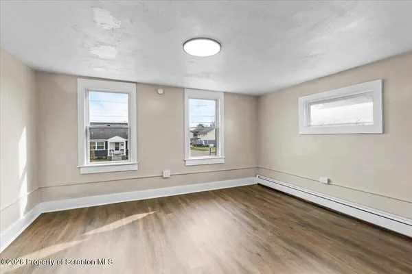 an empty room with wooden floor and windows
