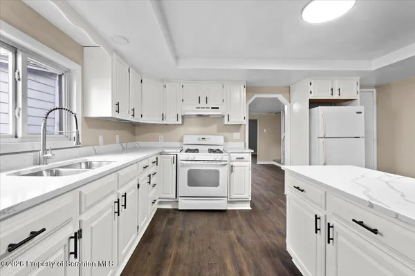 a kitchen with a refrigerator a sink and wooden floor