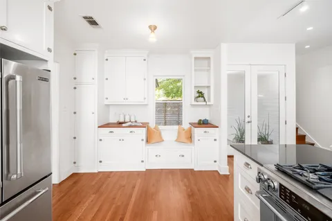 a large white kitchen with a stove a refrigerator a sink dishwasher and white cabinets with wooden floor